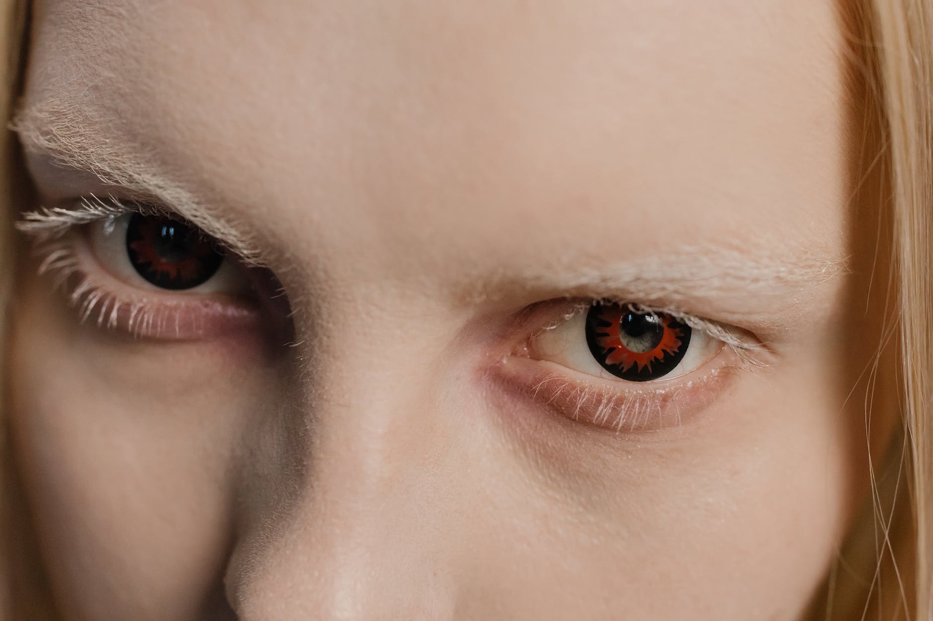 Close up shot of a person wearing creepy contact lenses and with frosted eyebrows.
